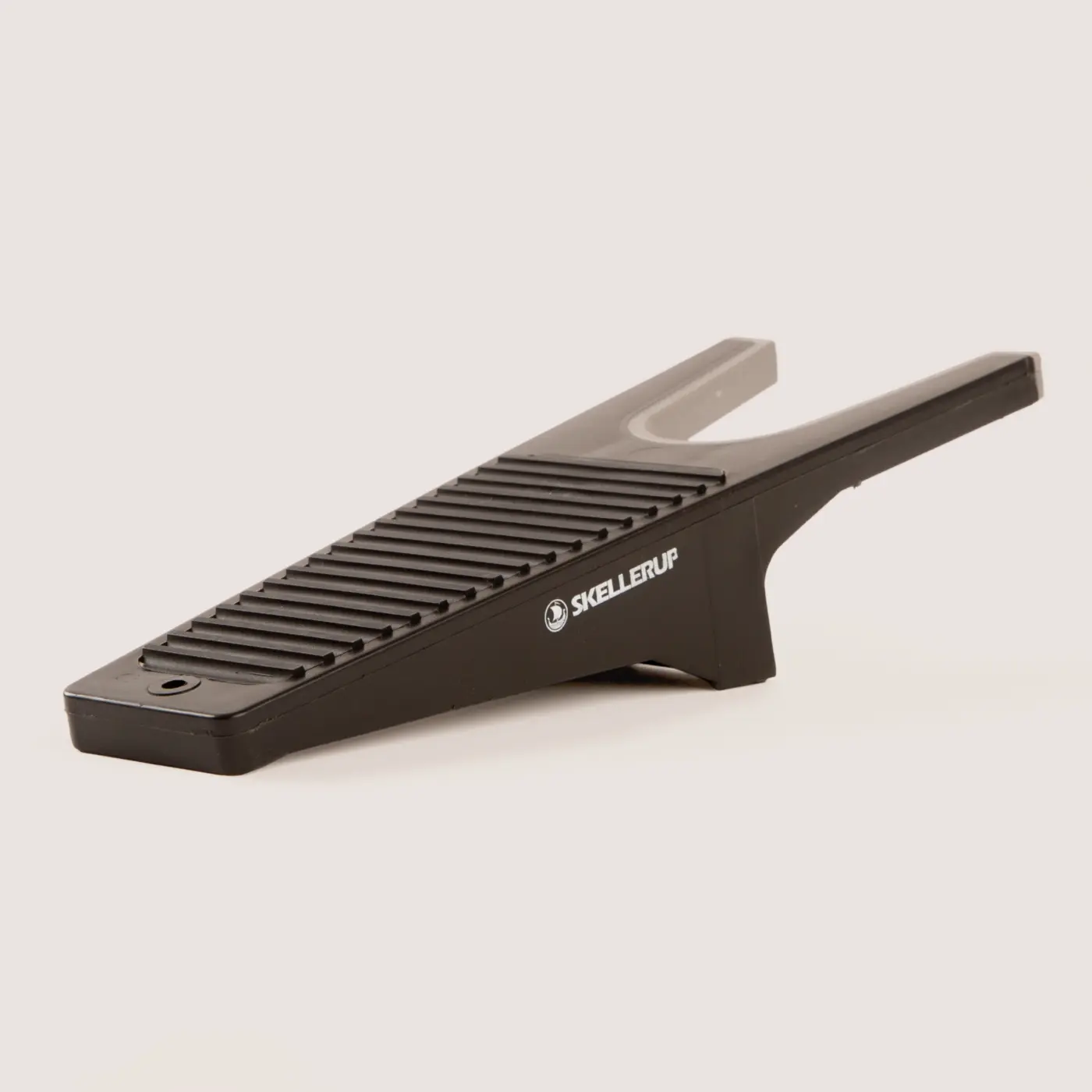 A black plastic boot remover with a ribbed surface and the brand name “Skellerup” printed on the side, designed to help remove boots hands-free.