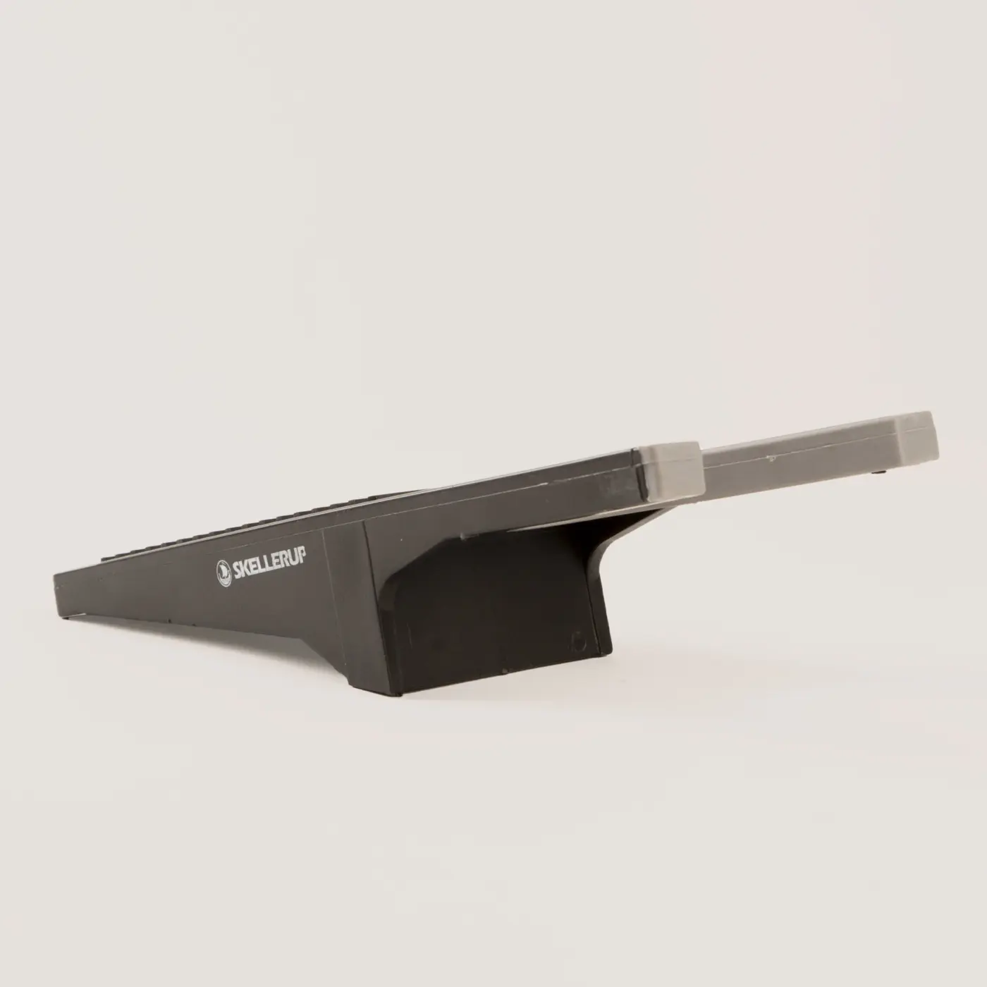 A black plastic boot remover with a textured surface, branded SKELLERUP, designed for removing boots.