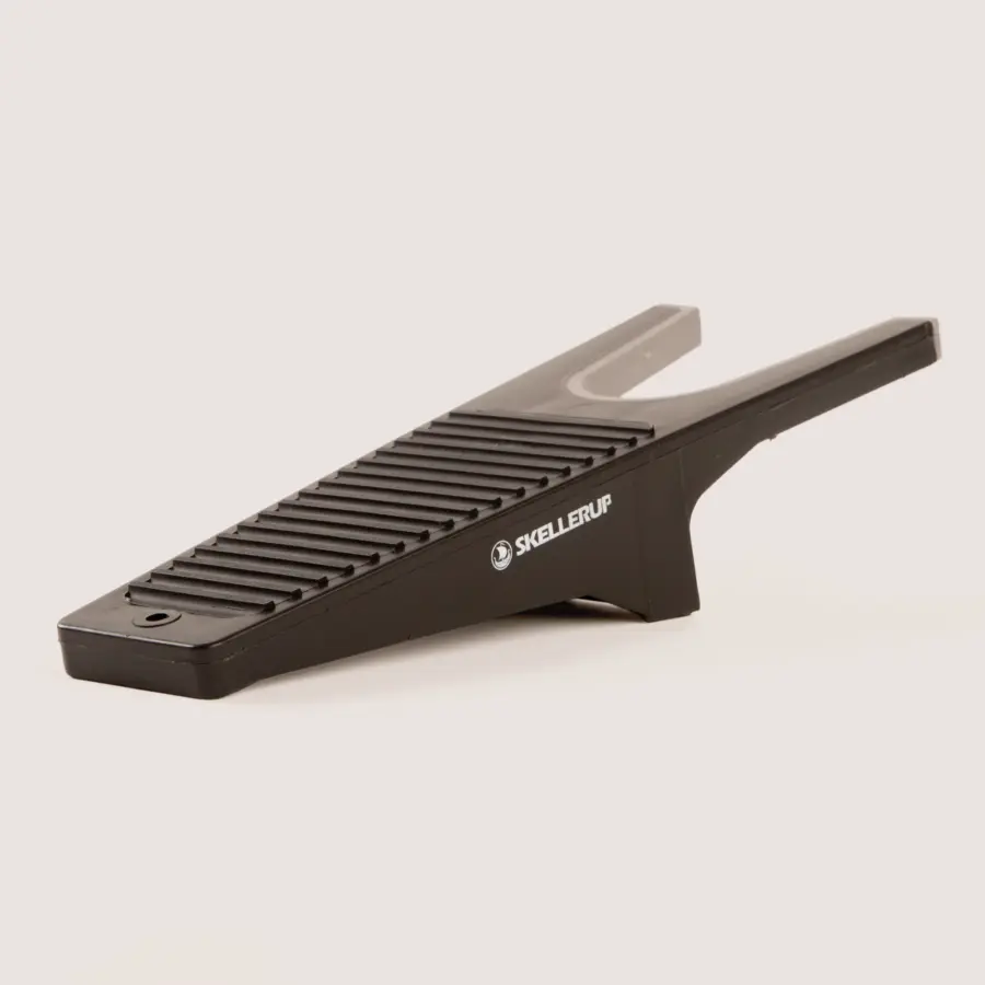 A black plastic boot remover with a ribbed surface and the brand name “Skellerup” printed on the side, designed to help remove boots hands-free.