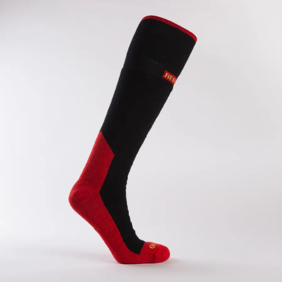 A single knee-high sock displayed on a mannequin leg, featuring a black body with red accents at the toe, heel, sole, and top cuff, and a small yellow logo near the top.