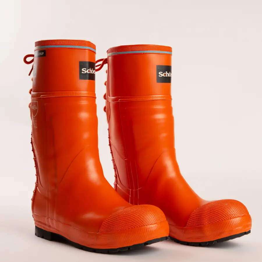 A pair of bright orange rubber boots with black soles and blue trim, standing upright on a light background. The boots have brand labels on the front near the top.