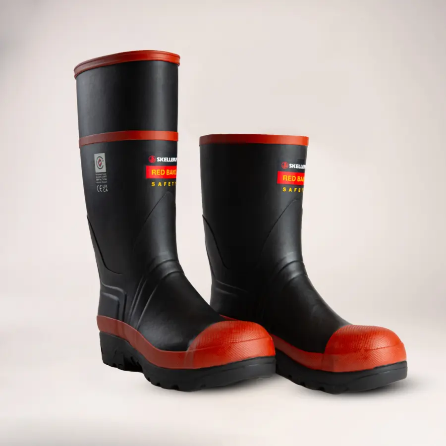 A pair of black and red safety boots with a thick sole and reinforced toe, labeled Red Band Safety on the side, displayed on a plain light background.