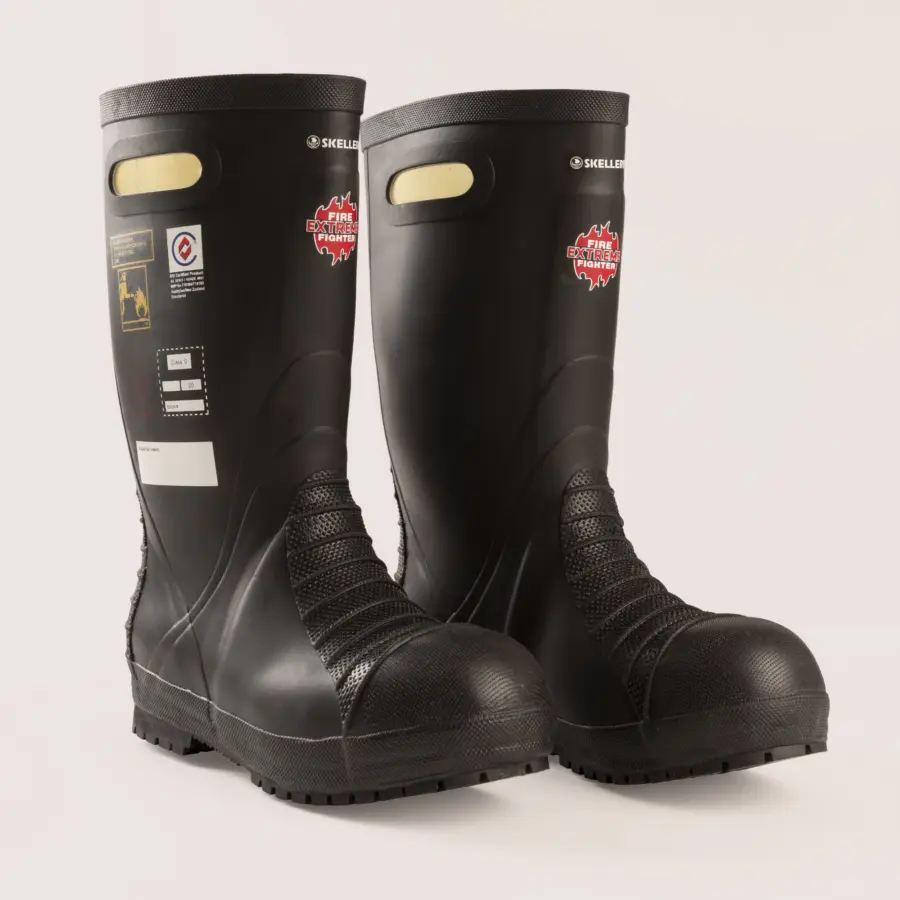 A pair of black firefighter boots with textured soles and labels on the front, including a red emblem and safety certification stickers, are displayed on a light background.