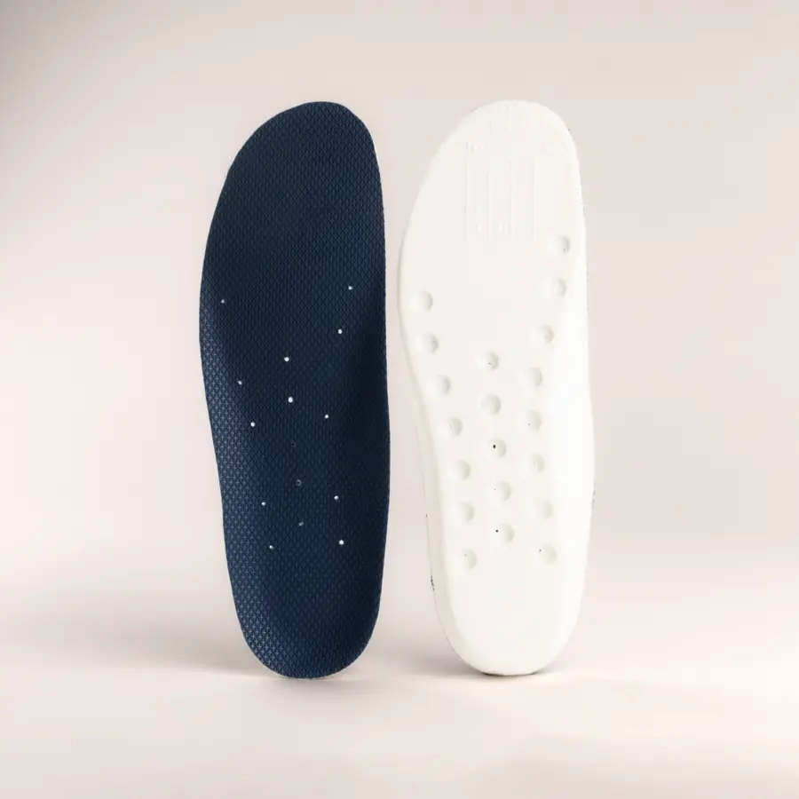 Two shoe insoles are shown side by side; the left one is dark blue with small perforations, and the right one is white with a textured pattern and raised bumps. Both are displayed on a plain light background.