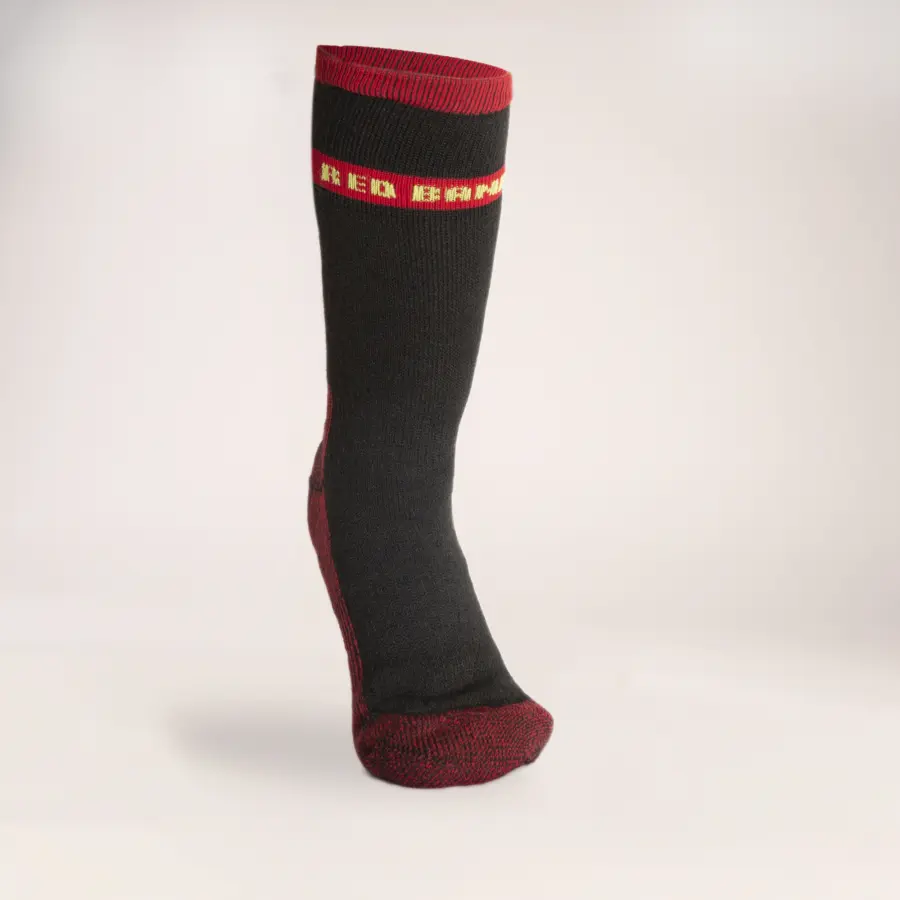 A single black knee-high sock with red accents at the top, toe, and heel, and a yellow and red patterned band near the cuff, displayed upright on a plain light background.