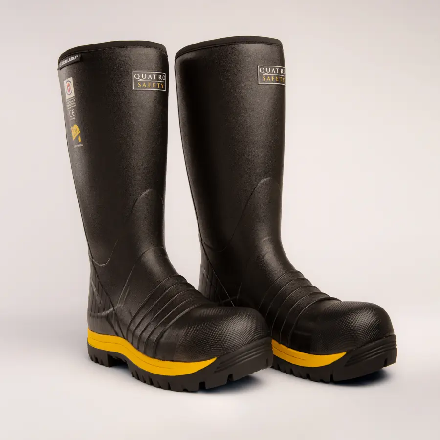A pair of black rubber safety boots with a yellow stripe on the soles, standing side by side on a plain light background. The boots have textured toes and the label Quatro Safety near the top.