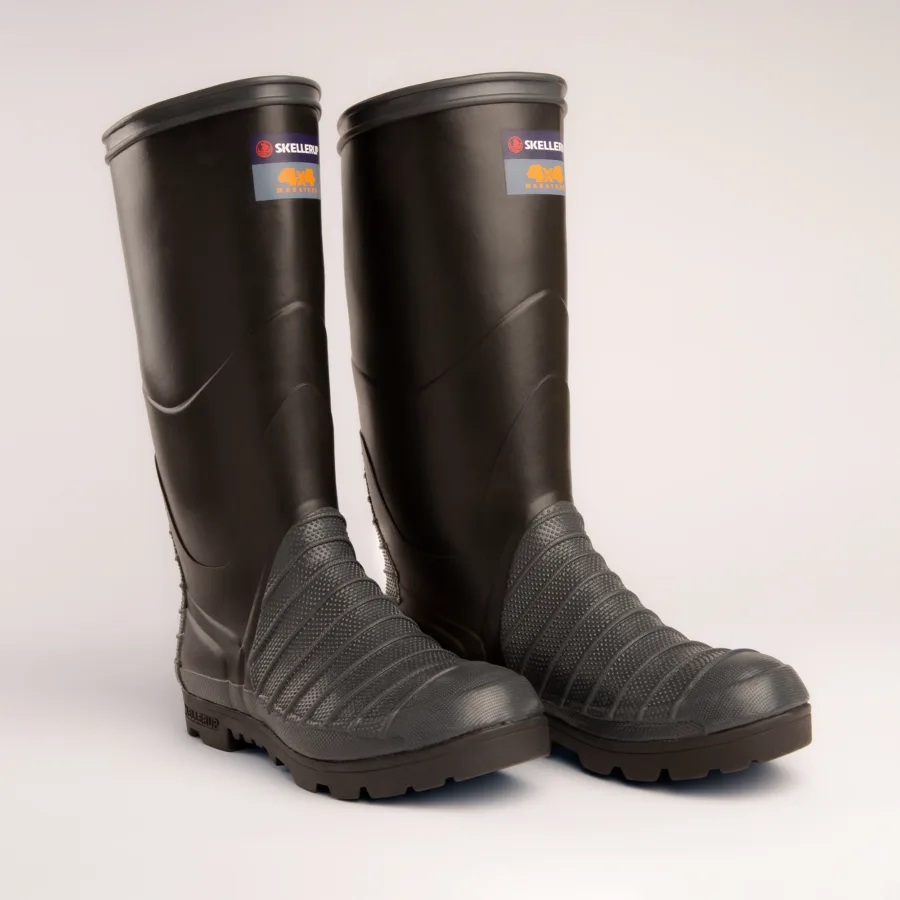 A pair of tall, black rubber work boots with textured soles and reinforced toe areas, standing side by side on a plain white background. Labels are visible near the top of each boot.