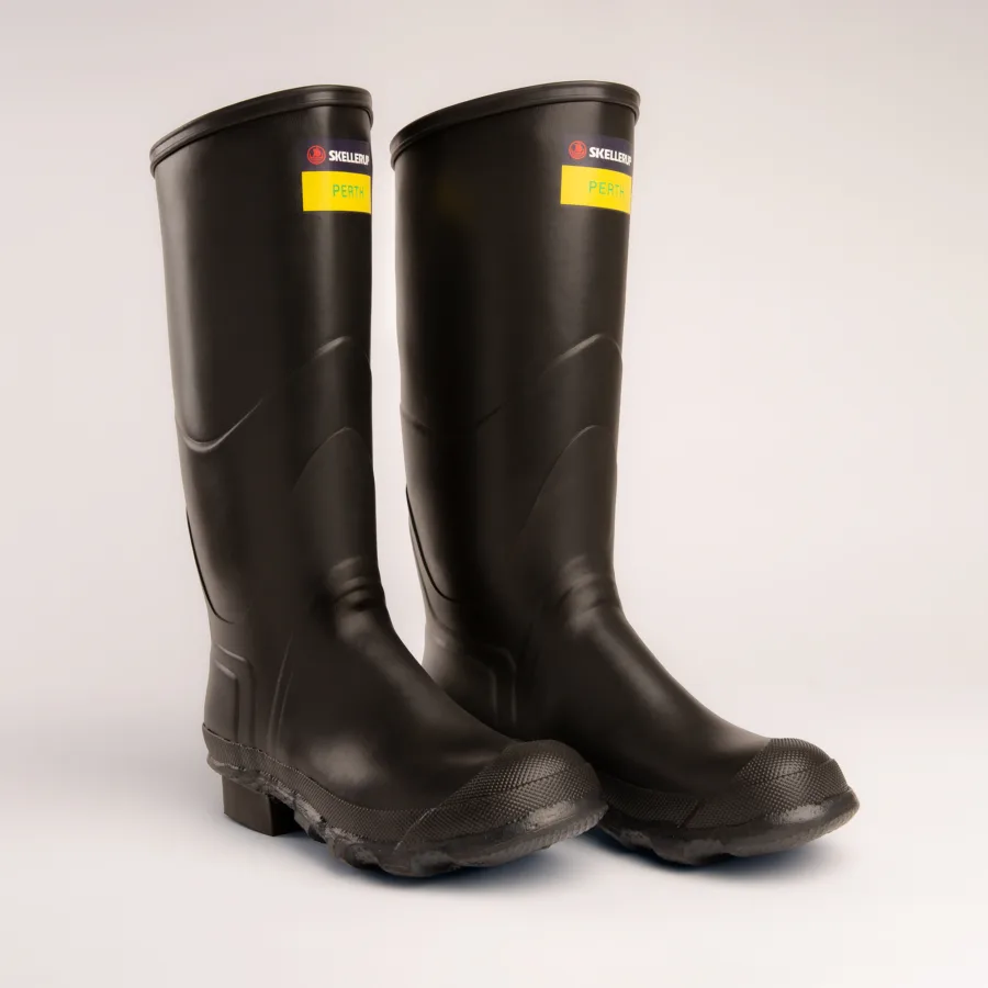 A pair of tall black rubber boots with textured soles, labeled SKELLERUP and PERTH on yellow tags near the top, standing upright on a plain light background.