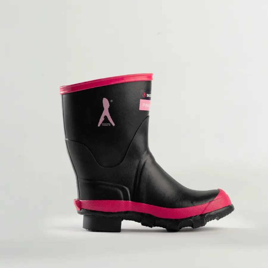 A black rain boot with pink accents around the top edge, sole, and toe, featuring a small pink ribbon and walking figure graphic on the side, photographed against a plain light background.