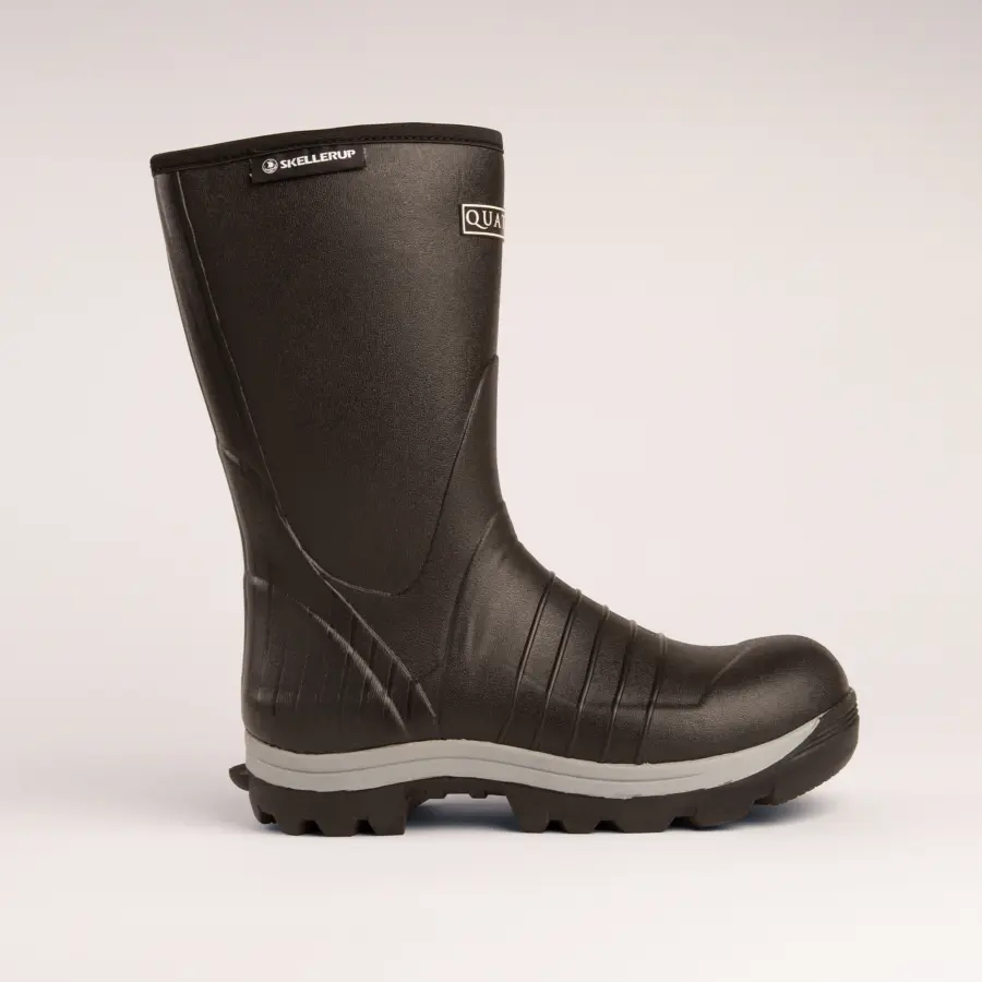 A black rubber work boot with textured surface, thick gray sole, and reinforced toe, shown in profile view on a plain light background.