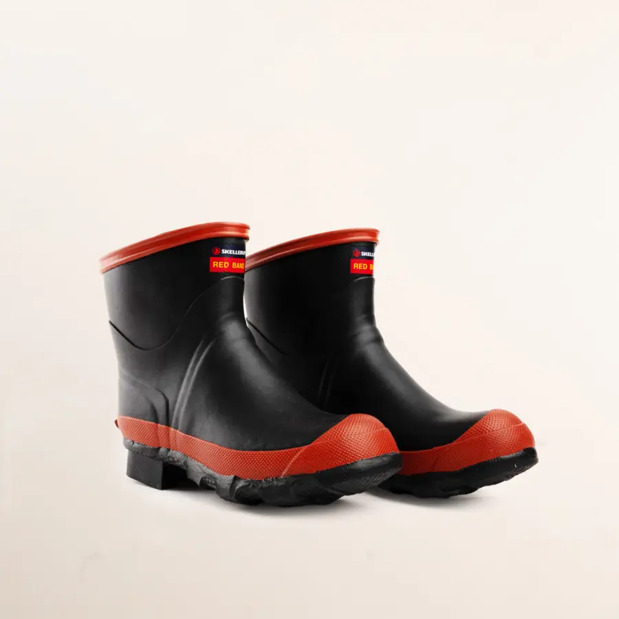 A pair of black rubber boots with red soles and red trim at the top, positioned side by side on a plain white background.