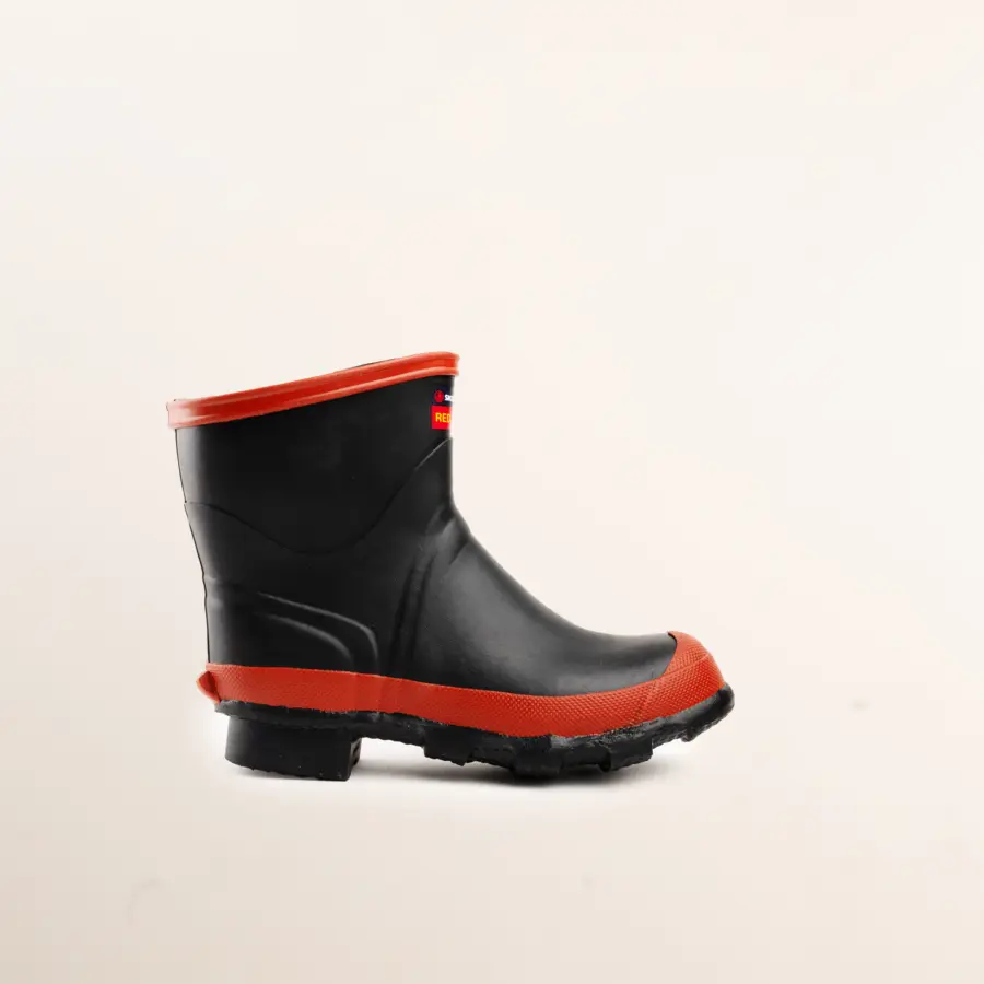 A single black rubber boot with a thick red sole and red trim around the top, displayed on a plain, light background.
