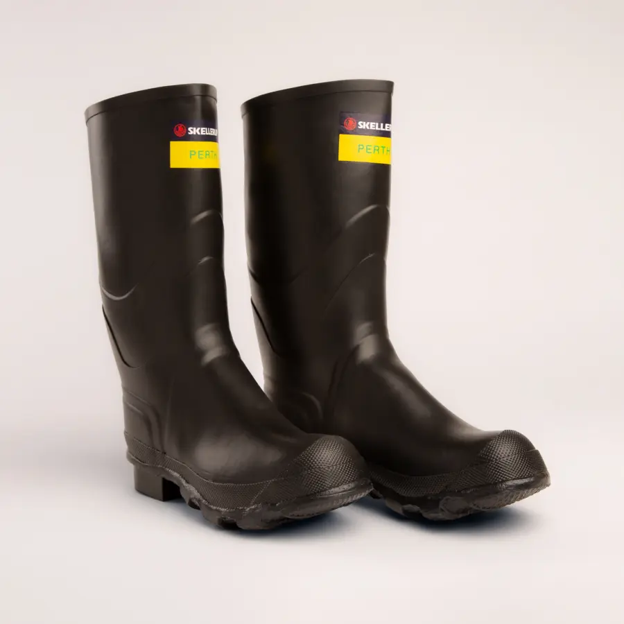 A pair of black rubber work boots with a yellow label that reads PERTH and a red logo on the upper shaft, displayed on a plain light background.